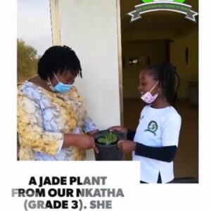 A student presents a flower pot gift to the school.